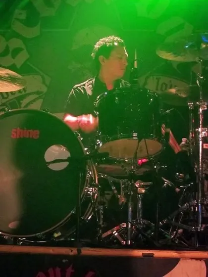 Sonny Sanchez playing drums in green stage light